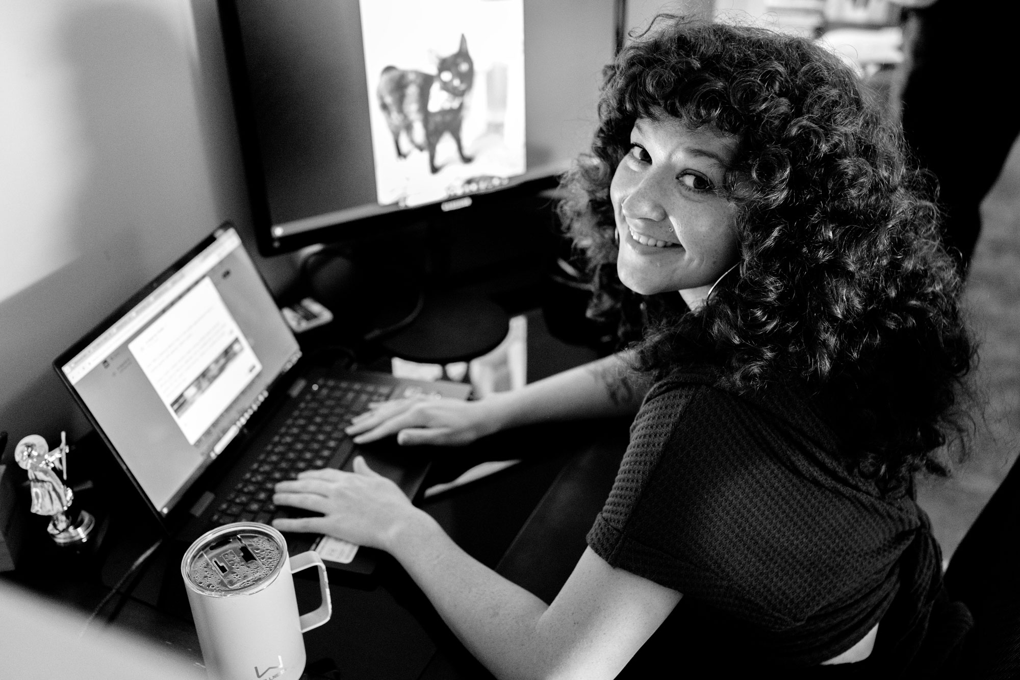 Marketing professional smiling while working on a laptop, symbolizing the personalized approach to small business marketing.